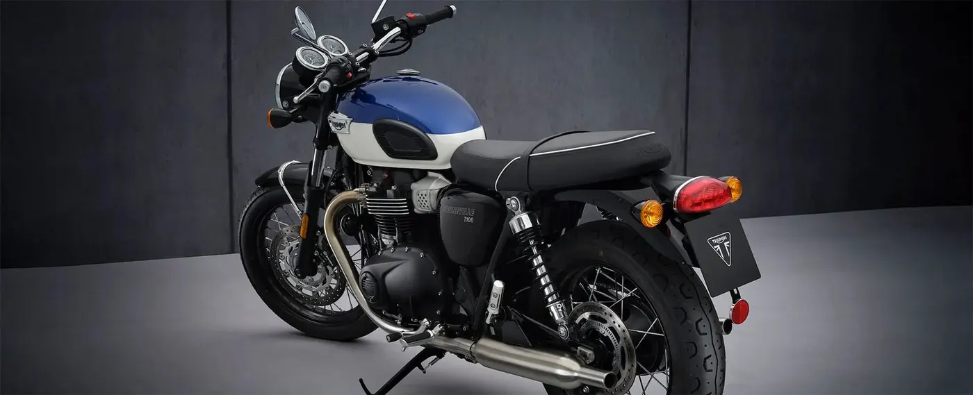 Triumph Bonneville T100 rear three-quarter view showing the seat and exhausts