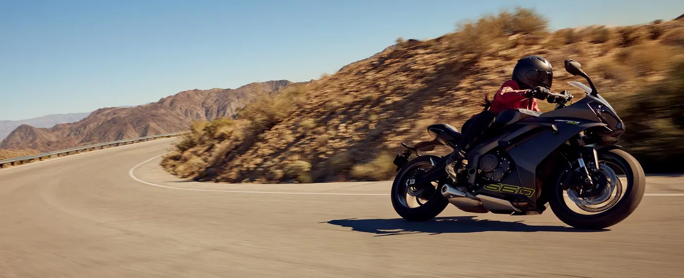 Triumph Daytona 660 cornering on a mountain road, side view