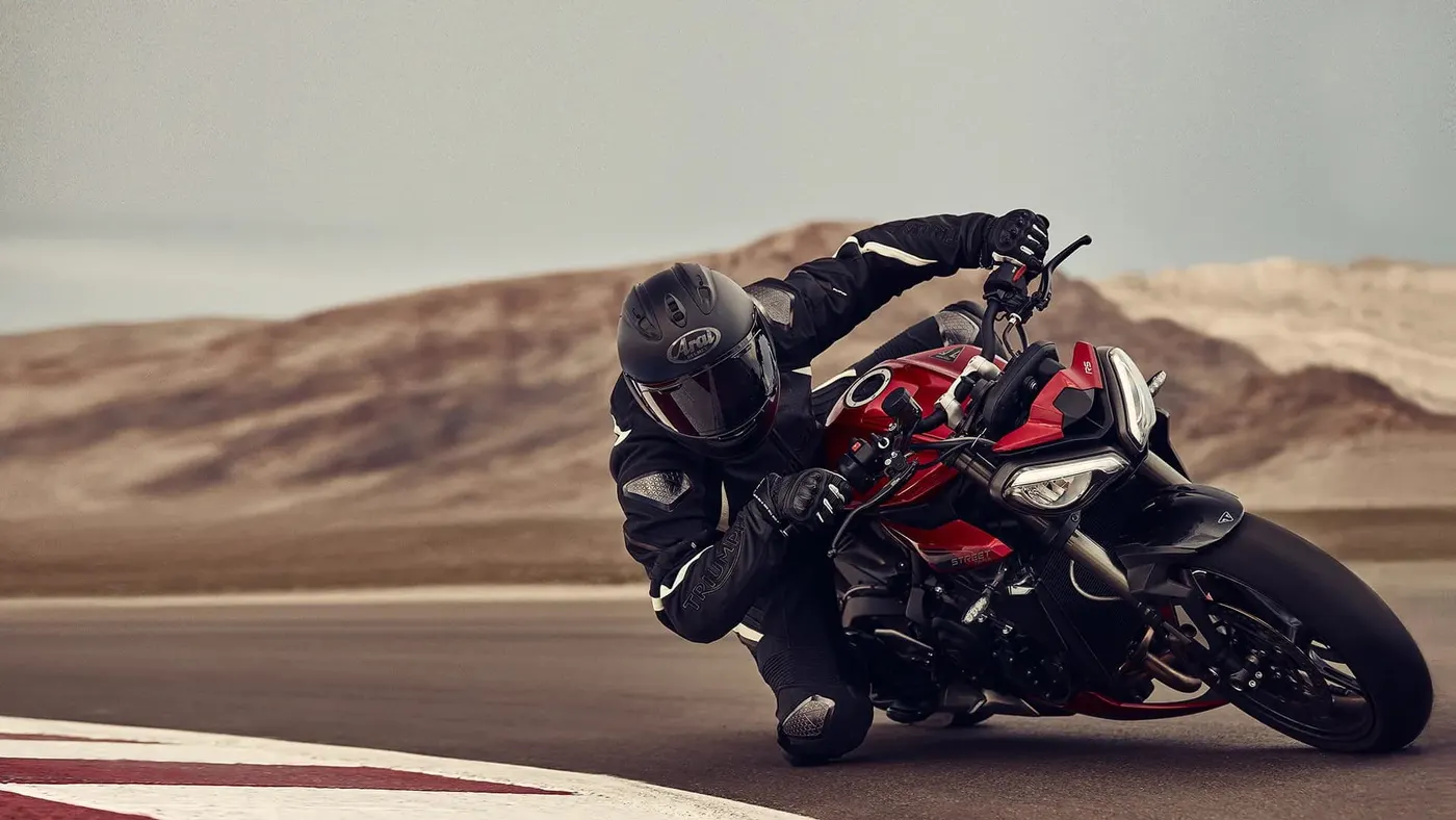 Red Triumph Street Triple 765 cornering hard on a circuit